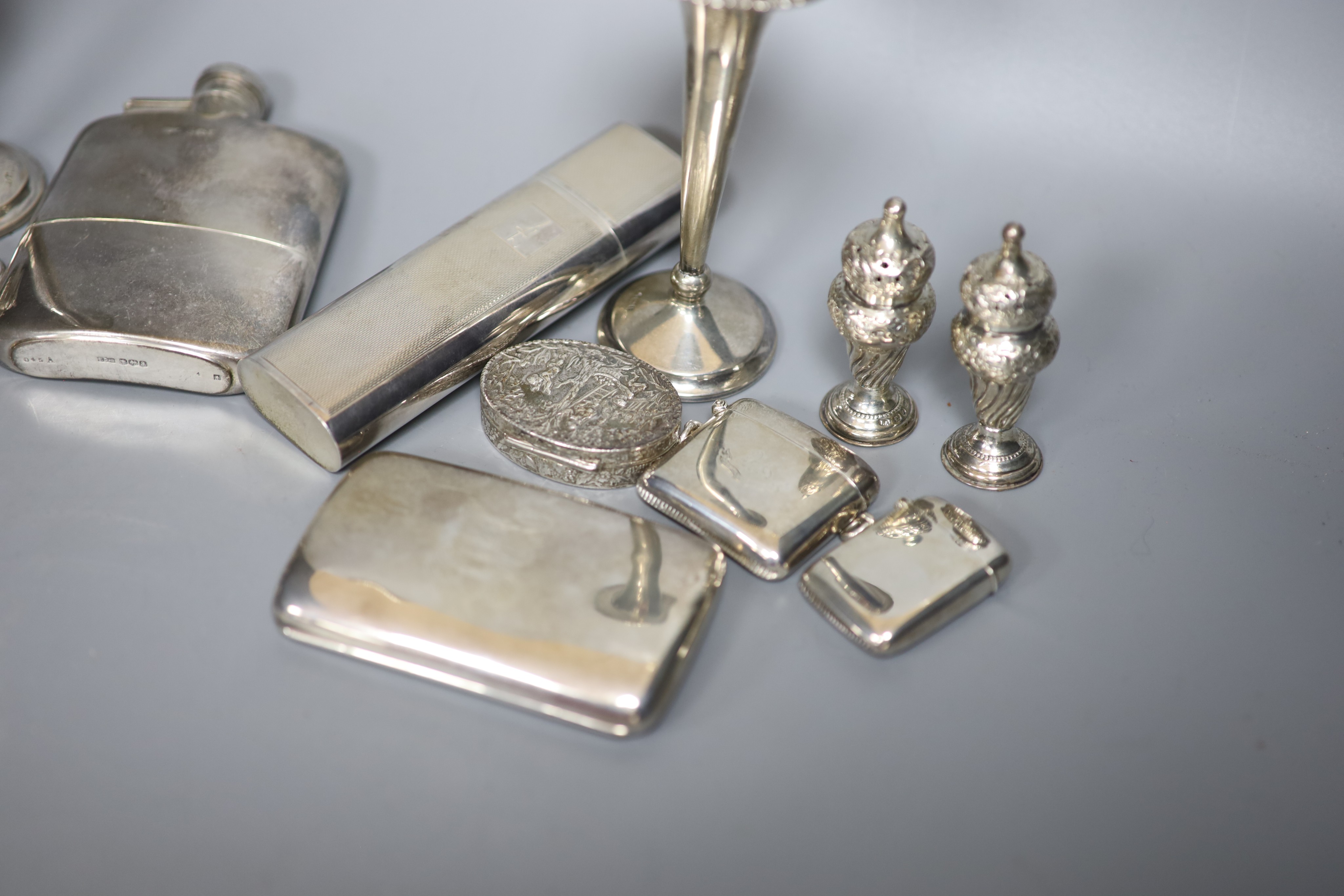 A group of assorted silver including two hip flasks, two spill vases, condiments, vesta cases, cigarette case, scent flask etc.